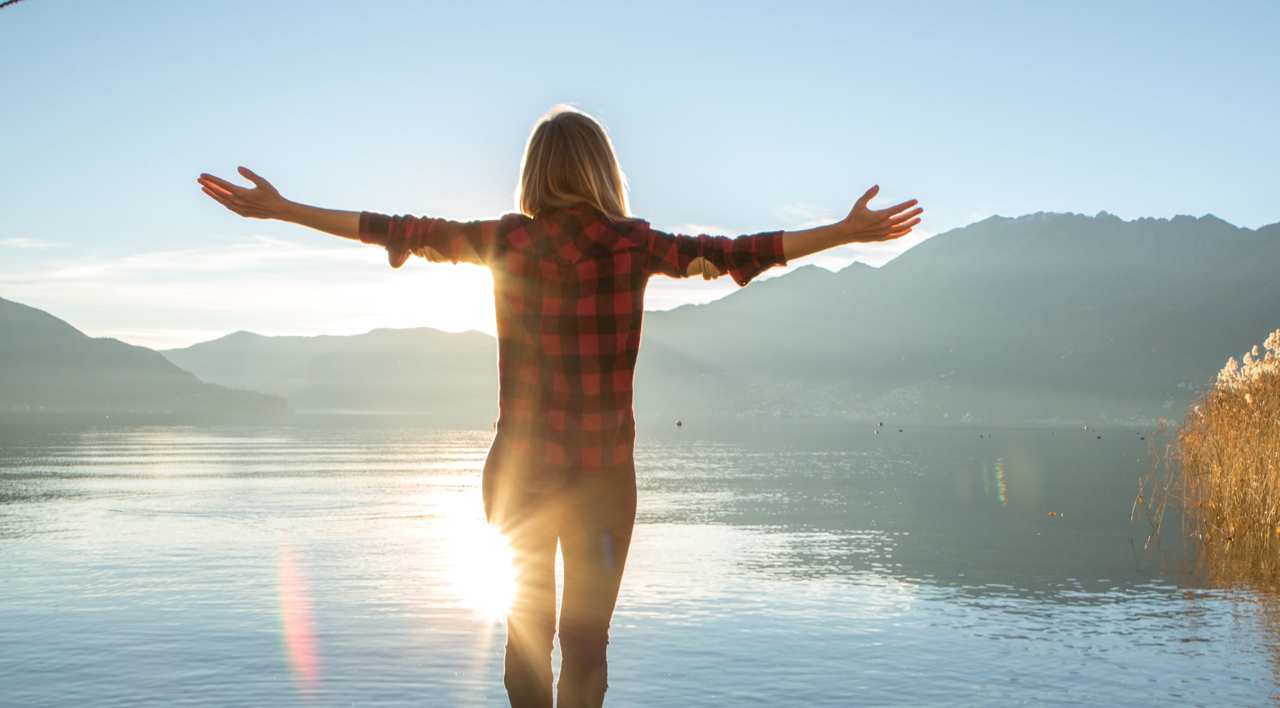 Young cheerful woman by the lake enjoying nature